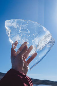 Close-up of hand holding ice cream against sky