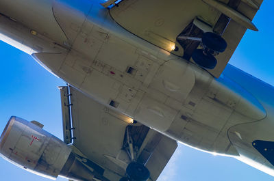 Low angle view of airplane wing against blue sky