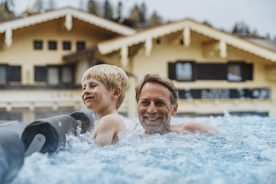 Cheerful son with father enjoying in infinity pool at hotel