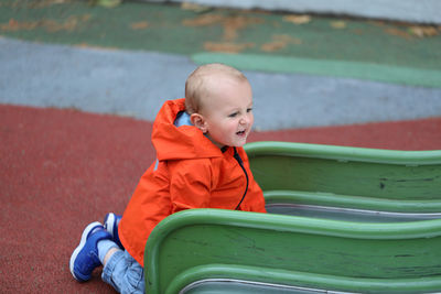 Cute boy looking away while sitting on floor