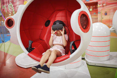 Full length of girl wearing virtual reality simulator at game zone