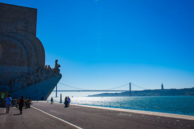 View of monument next to sea against clear blue sky 