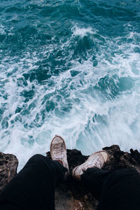 Low section of man standing on rock by sea