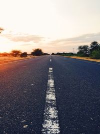 Road passing through field at sunset