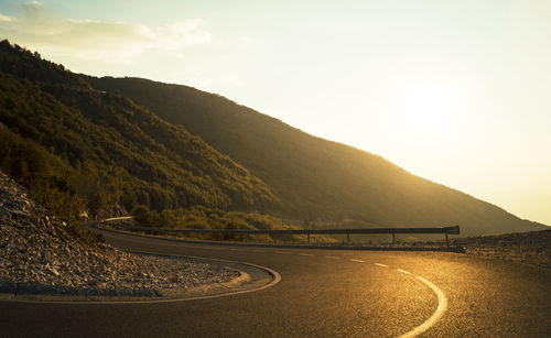 Scenic view of road by mountains against sky