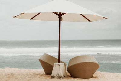 Deck chairs on beach against sky