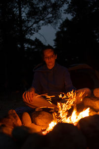 A woman reads a book by a campfire in nature. campfire on a hike in the forest. traveling