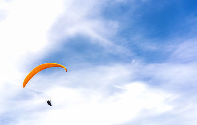Low angle view of person paragliding against sky