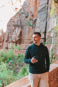 Young man standing against rock formations