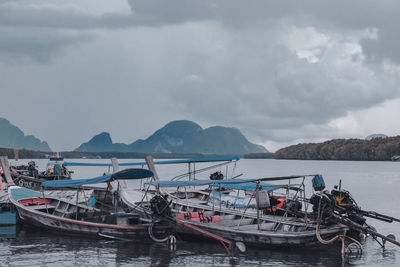 Fishing boats in sea against mountains