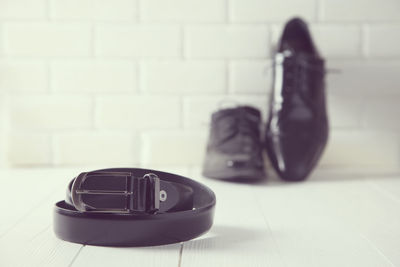 Close-up of leather belt and shoes on floor against wall