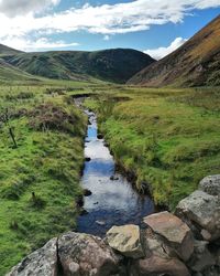 Stream flowing through rocks against sky