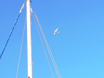 Low angle view of crane against clear blue sky