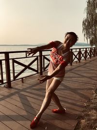 Full length of woman standing on railing against sea