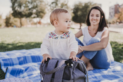 Mother and daughter sitting on picnic blanket at park
