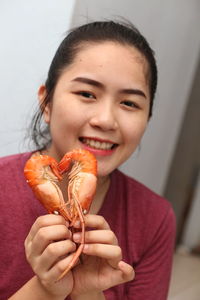 Portrait of smiling woman holding prawns