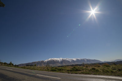 Road by mountains against clear blue sky