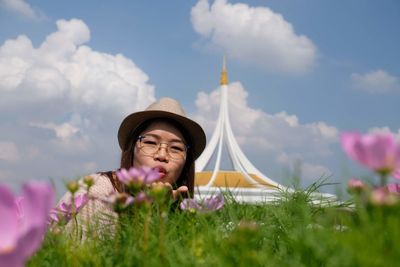 Portrait of woman by blooming flowers against tower