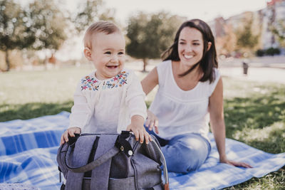 Mother and daughter sitting on picnic blanket at park
