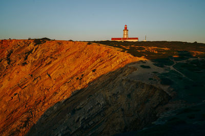 Lighthouse by sea against clear sky