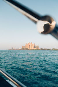 Sea by buildings against clear sky