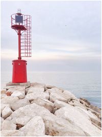 Lighthouse by sea against sky