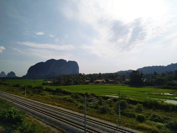 Railroad track amidst field against sky