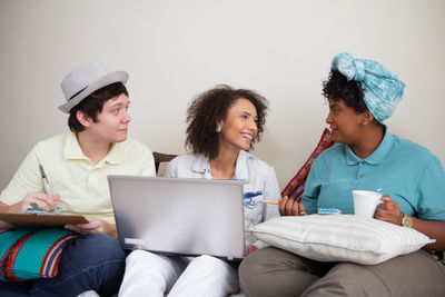 Young woman using phone while sitting on laptop