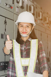 Portrait of smiling young woman standing against built structure