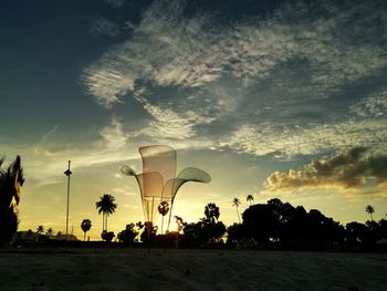 Silhouette palm trees on beach against sky at sunset