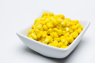 Close-up of yellow fruit salad in bowl against white background