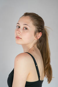 Portrait of young woman looking away against white background