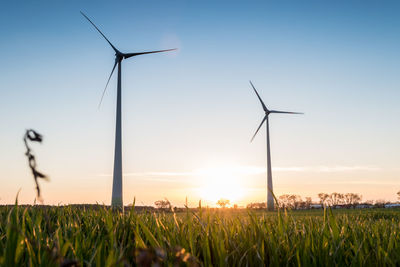 Windmill on field against sky during sunset