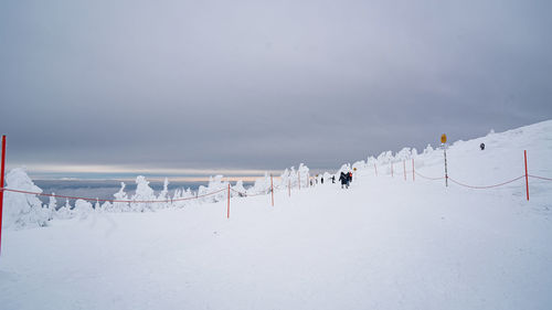 People on snow covered landscape against clear sky