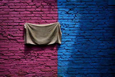 Towel hanging on colorful brick wall