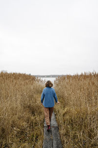 Young woman walking on boardwalk amidst grass