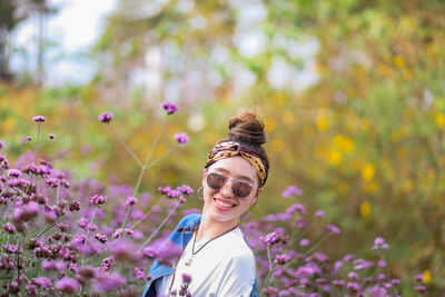 Portrait of young woman wearing sunglasses against pink flowering plants
