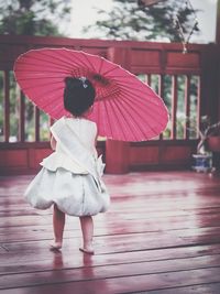 Rear view of woman standing on red umbrella