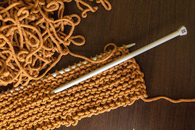 Directly above shot of wool with knitting needles at table