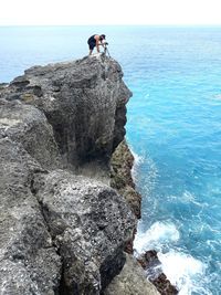 Rear view of man standing on rock by sea