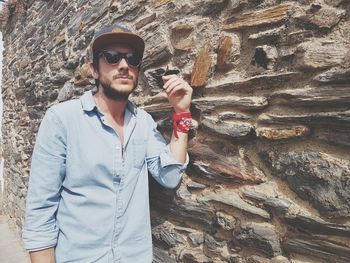 Portrait of young man wearing sunglasses standing on rock