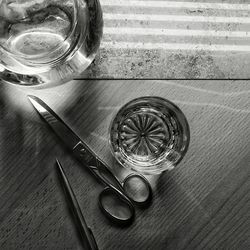 High angle view of scissor and glass on wooden table