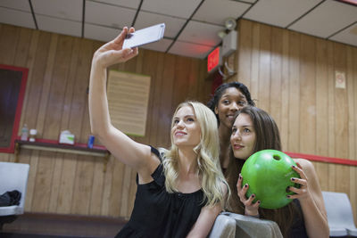 Two young woman taking a picture on a cell phone.