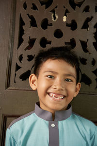 Portrait of malay boy in malay traditional cloth on against wooden craving background 