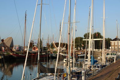Boats moored at harbor against clear sky