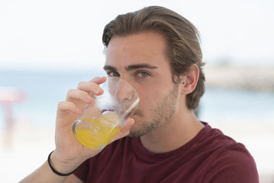 Portrait of young man drinking juice outdoors