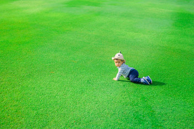 High angle view of boy crawling on grass at park