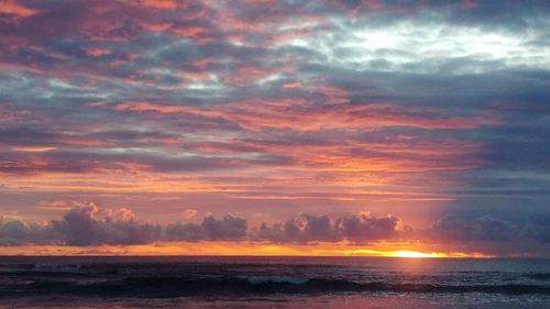 Scenic view of sea against dramatic sky during sunset