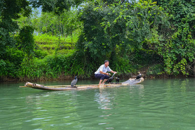 People in boat on lake against trees