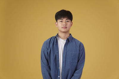 Portrait of boy standing against yellow background